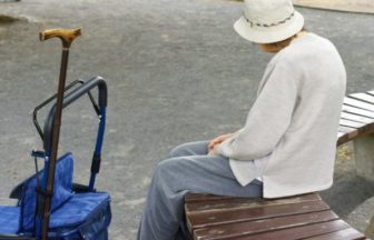 公園のベンチに座って休む高齢者